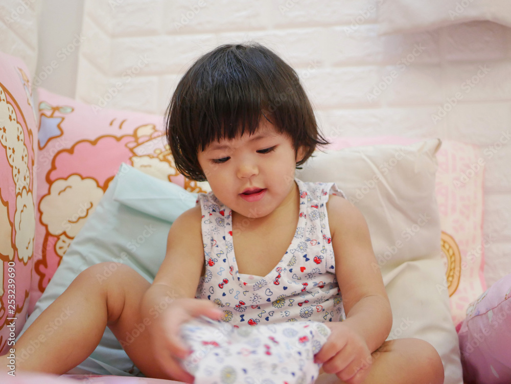 Little Asian baby girl, 23 months old, learning to put on short pants by herself - child development by allowing them to do things by themselves Little Asian baby girl, 23 months old, learning to put on short pants by herself - child development by allowing them to do things by themselves