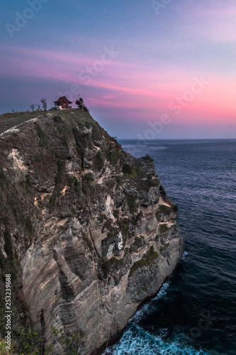 Pink sunset at Atuh beach on Nusa Penida island in Indonesia with a lone cliff top house