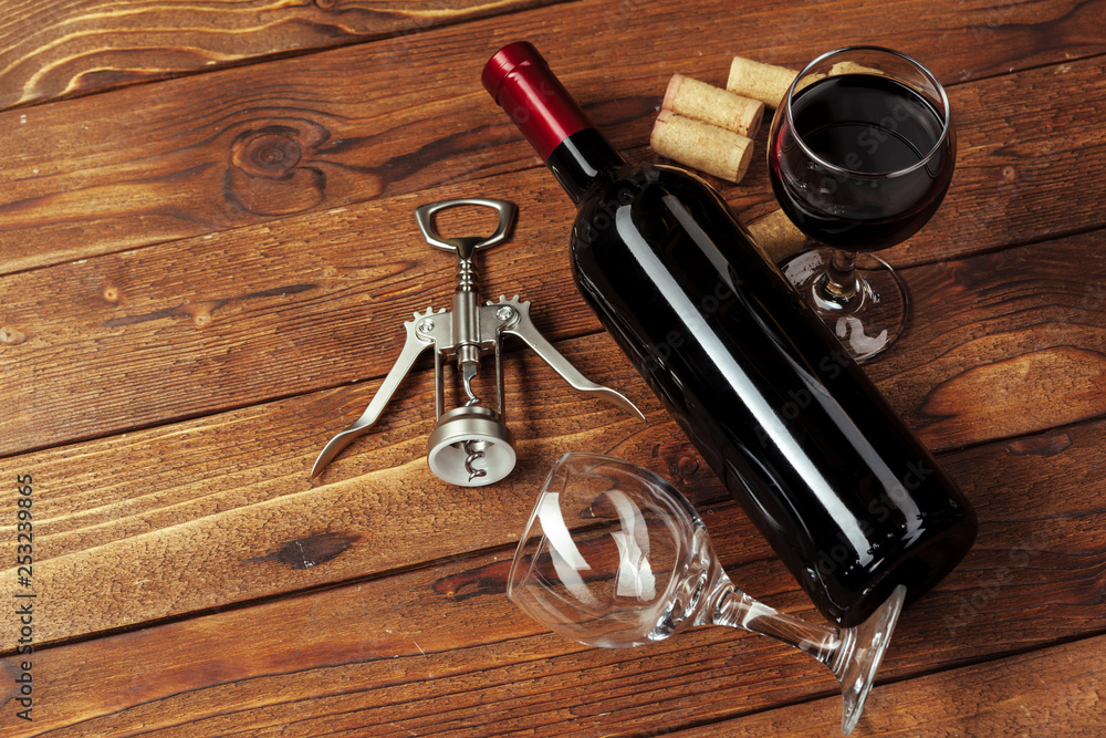 Red wine bottle, wine glass and corkscrew on wooden table background Red wine bottle, wine glass and corkscrew on wooden table background