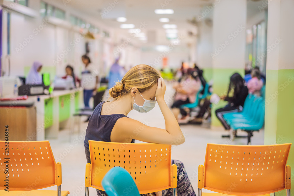 Young woman sitting in hospital waiting for a doctor's appointment. Patients In Doctors Waiting Room