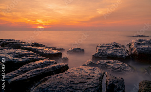 Fototapeta Naklejka Na Ścianę i Meble -  Rocks on stone beach at sunset. Beautiful beach sunset sky. Twilight sea and sky. Tropical sea at dusk. Dramatic sky and clouds. Sunset abstract background. Calm and relax life. Nature landscape.
