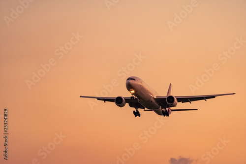 Commercial airline. Passenger plane landing at airport with beautiful sunset sky and clouds. Arrival flight. Airplane flying for landing. Aircraft open light in the evening flight. Night flight.