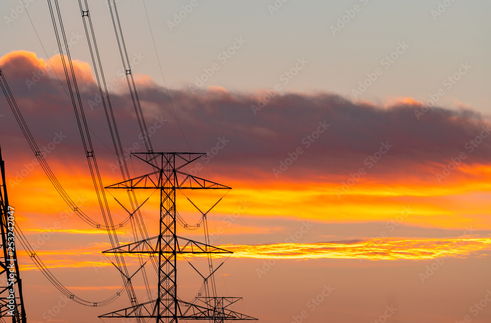 High voltage electric pole and transmission lines in the evening. Electricity pylons at sunset. Power and energy. Energy conservation. High voltage grid tower with wire cable at distribution station.