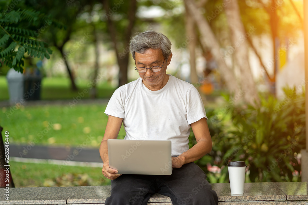 The elderly man used laptop in park The elderly man used laptop in park
