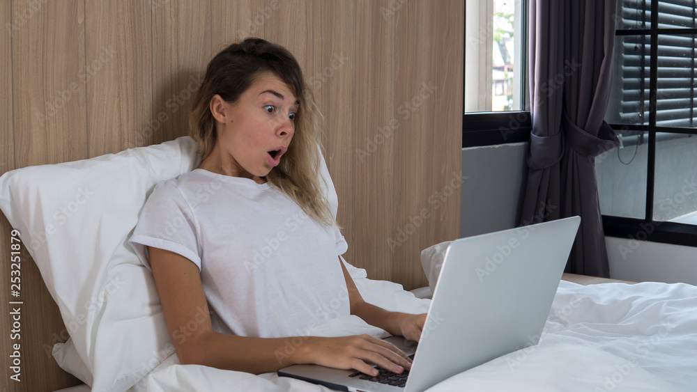attractive girl working on computer at home in bed,something amazing in internet attractive girl working on computer at home in bed,something amazing in internet