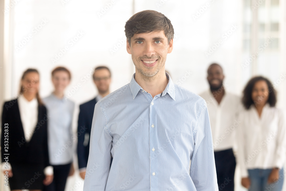 Smiling male employee standing in office looking at camera Smiling male employee standing in office looking at camera
