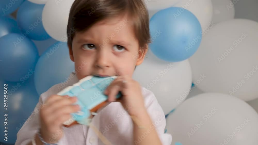 boy child of two years eating a festive blue cake with a car boy child of two years eating a festive blue cake with a car