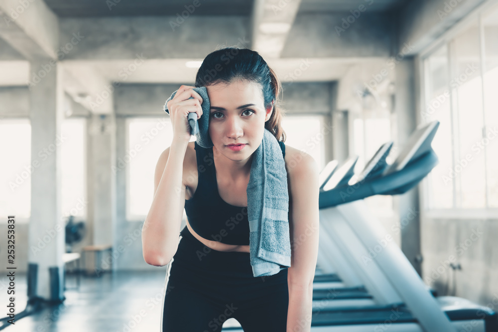 Beautiful Athletic Woman is Wiping Sweat With Towel in Gym, Portrait of Pretty girl in Sportswear is Exercising in Fitness Club. Sport Lifestyle and Healthy Concept.