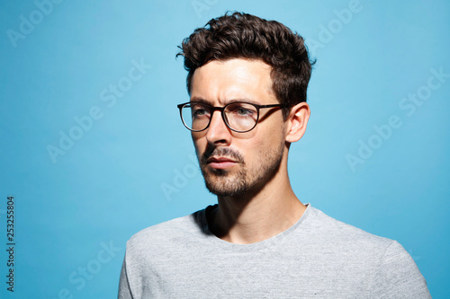 Close up of thoughtful young man wearing eyeglasses