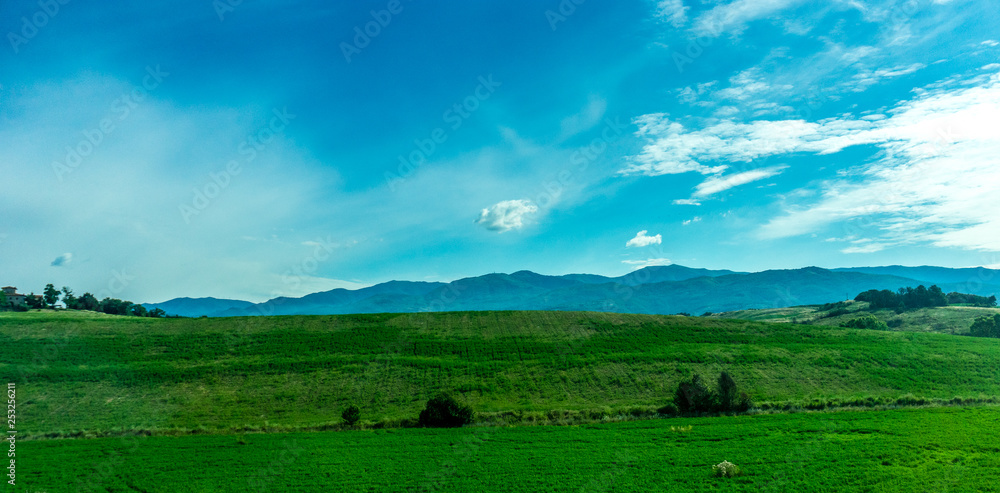 Italy, Rome to Florence train, a large green field with a mountain in the background