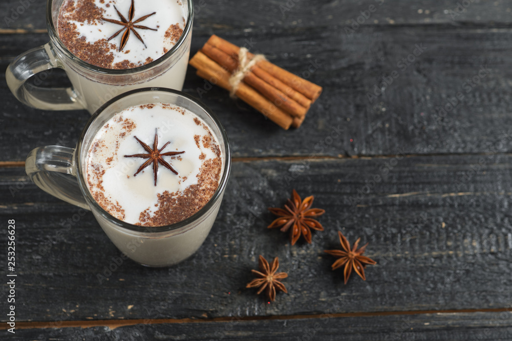 Homemade tea latte with cinnamon and anise on wooden rustic black background in glass mug Homemade tea latte with cinnamon and anise on wooden rustic black background in glass mug