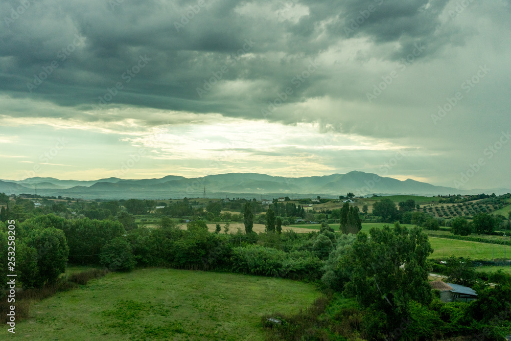 Naklejka premium Italy, Rome to Florence train, a large green field with clouds in the sky