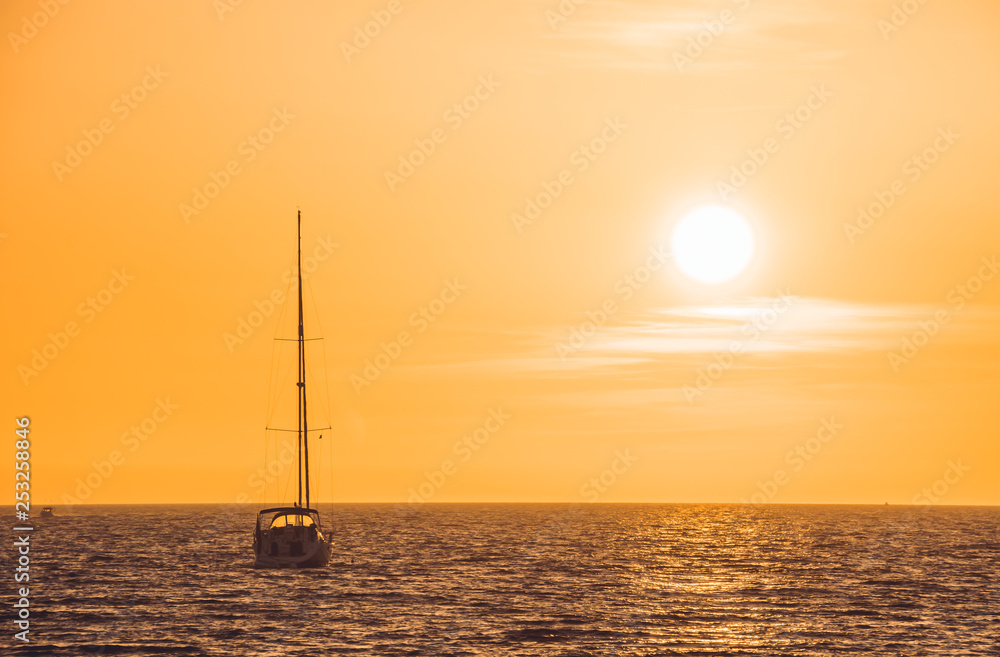 Little white boat floating on the water towards the horizon in the rays of the setting sun Little white boat floating on the water towards the horizon in the rays of the setting sun