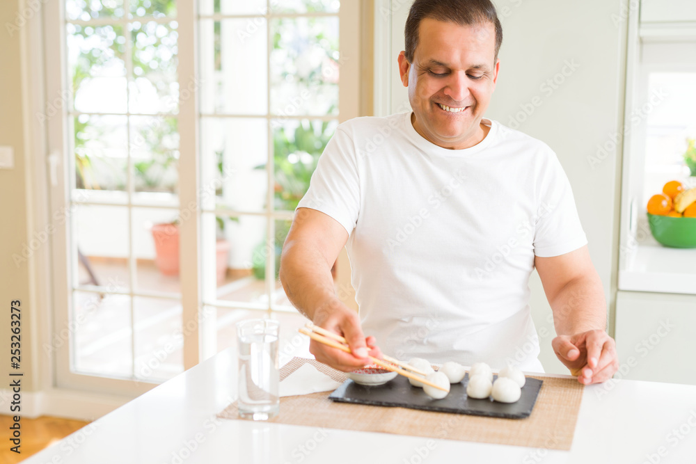 Middle age man eating asian dim sum using chopsticks at home Middle age man eating asian dim sum using chopsticks at home