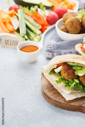 Pita breads with falafel, fresh vegetable sticks and sauce.