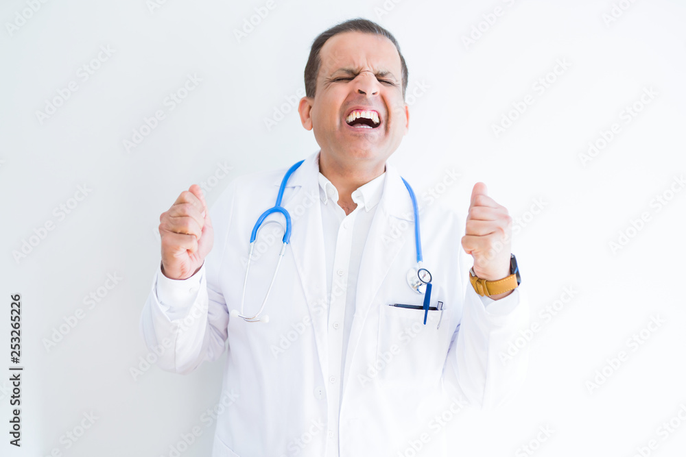Middle age doctor man wearing stethoscope and medical coat over white background excited for success with arms raised celebrating victory smiling. Winner concept. Middle age doctor man wearing stethoscope and medical coat over white background excited for success with arms raised celebrating victory smiling. Winner concept.