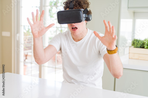 Young man having fun wearing virtual reality glasses at home