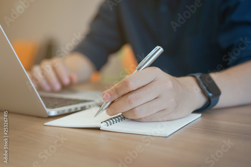 close up man hand writing and using laptop 