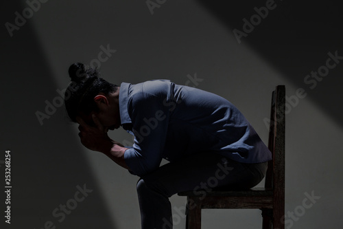 An Asian man is suffering from depression in darkness.