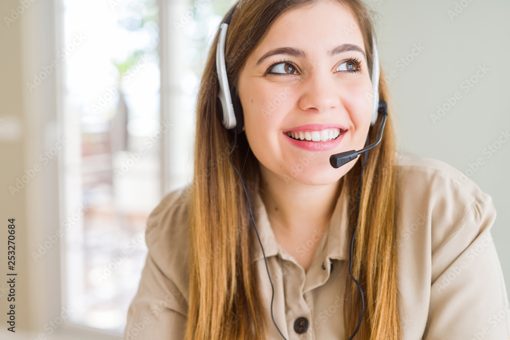 Beautiful young operator woman wearing headset at the office smiling looking side and staring away thinking. Beautiful young operator woman wearing headset at the office smiling looking side and staring away thinking.