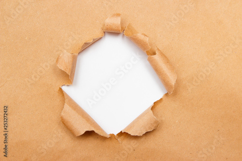 Hole into brown craft paper sheet with torn edges. White center isolated, clipping path included. Top view.