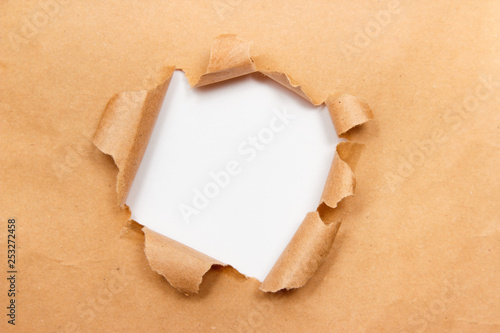 Hole into brown craft paper sheet with torn edges. White center isolated, clipping path included. Top view.