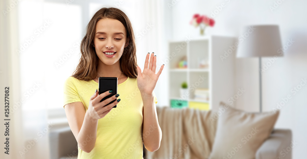 technology and people concept - smiling young woman or teenage girl in blank yellow t-shirt having video call smartphone over home living room background technology and people concept - smiling young woman or teenage girl in blank yellow t-shirt having video call smartphone over home living room background