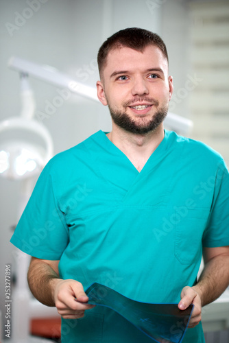 Caucasian male dentist holding xray in hands and smiling