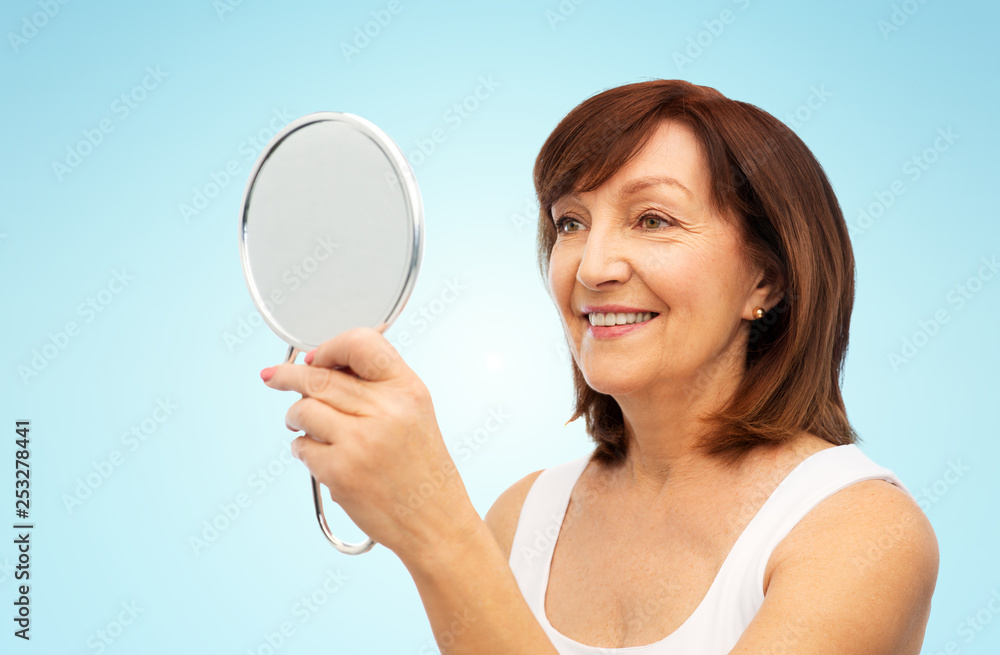 beauty and old people concept - portrait of smiling senior woman with mirror over blue background beauty and old people concept - portrait of smiling senior woman with mirror over blue background