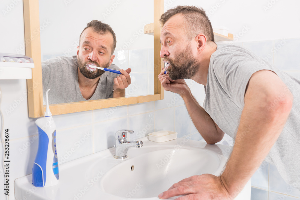 Obraz premium Man brushing his teeth in bathroom