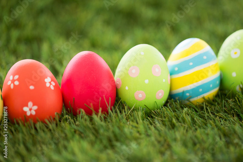 easter  holidays and tradition concept - row of colored eggs on artificial grass