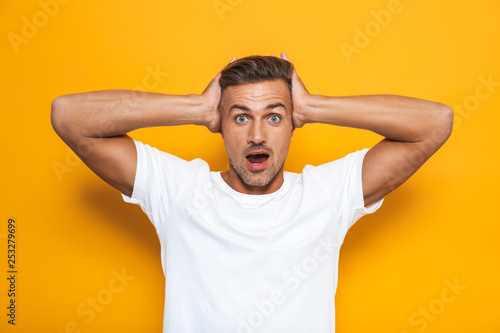 Shocked excited man posing isolated over yellow wall background.