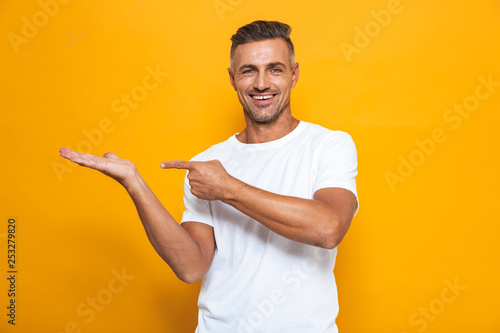 Fotografija Happy excited man posing isolated over yellow wall background pointing