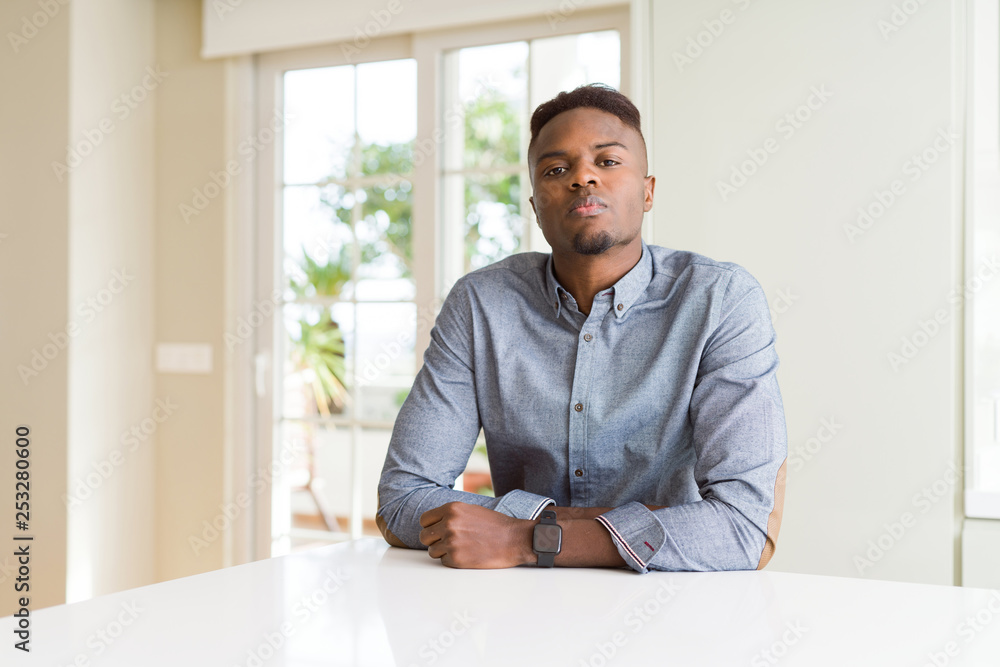 Handsome african american man on white table Relaxed with serious expression on face. Simple and natural looking at the camera.