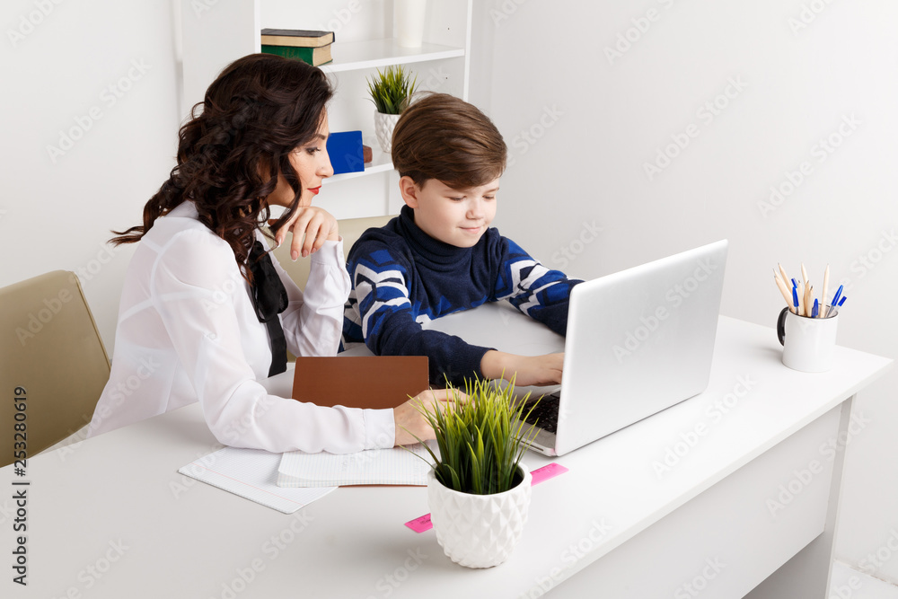Doing homework on the laptop. Child doing homework and his teacher helps Doing homework on the laptop. Child doing homework and his teacher helps