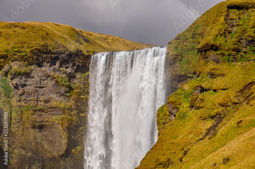 Widok na wodospad w Islandii. Woda przepływa z góry na dół.