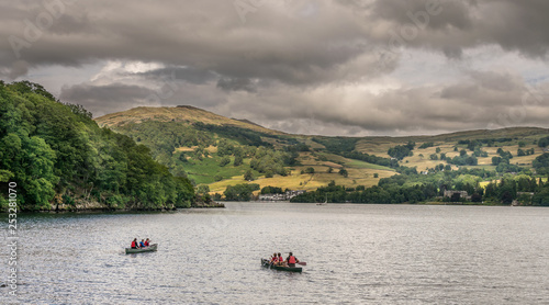 people canoeing on a lake in the lake district, with storm clouds gathering. 