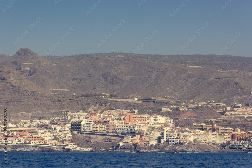 Ocean port town situated under sheer cliffs - view from boat.