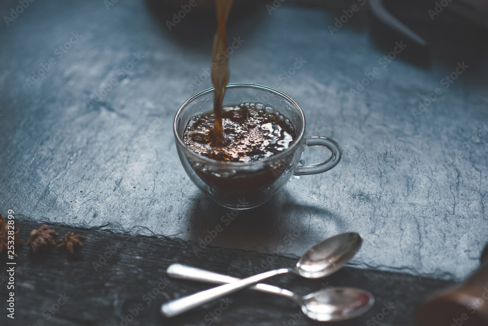 Fototapeta premium Pouring a coffee from french press to coffee mug on a stone, dark background. 