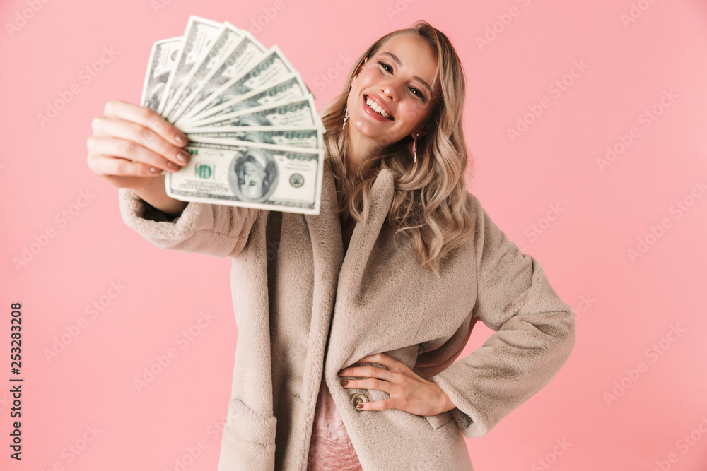Young pretty woman posing isolated over pink wall background holding money. Young pretty woman posing isolated over pink wall background holding money.