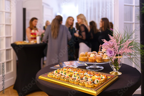 Delicious snacks on catering table during corporate event party - brunch choice of food with blurred group of people in background enjoying time together at business event party, Catering Food Concept