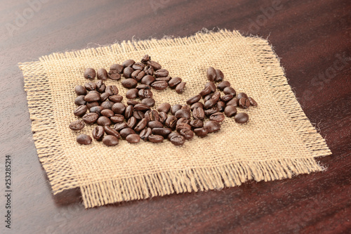 Vintage coffee background. Roasted coffee beans on real jute burlap napkin.