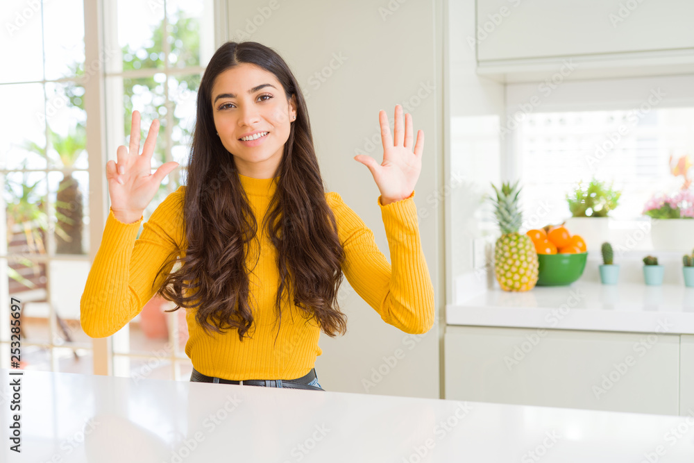 Young beautiful woman at home on white table showing and pointing up with fingers number eight while smiling confident and happy. Young beautiful woman at home on white table showing and pointing up with fingers number eight while smiling confident and happy.