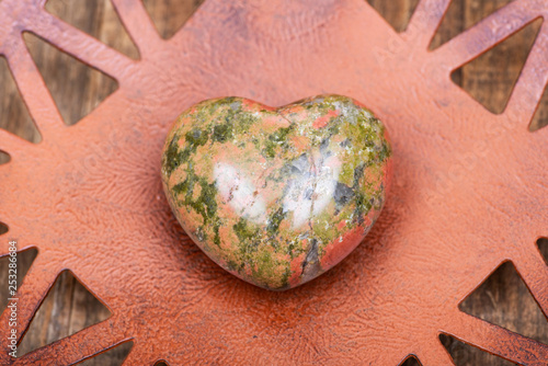 Highly polished puffy Unakite Heart from Unakas Mountains in North Carolina, on Rustic Orange decorative plate. photo