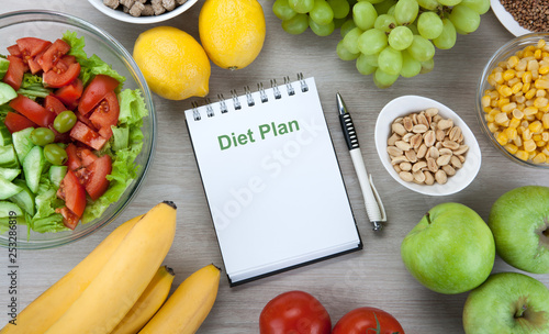 notebook with a diet plan with fresh vegetables and fruits on the table
