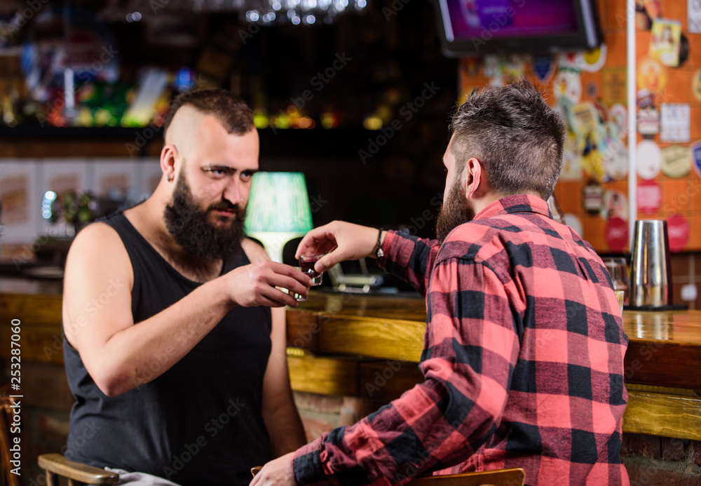 Men relaxing at pub. Strong alcohol drinks. Friday relax in pub. Friends relaxing in pub. Drunk conversation. Cheers concept. Hipster brutal bearded man drinking alcohol with friend at bar counter