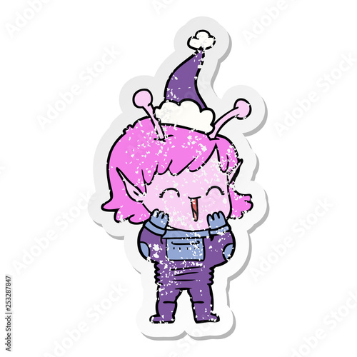 distressed sticker cartoon of a alien girl giggling wearing santa hat