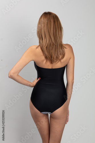 Woman torso with long hair in black body from behind.