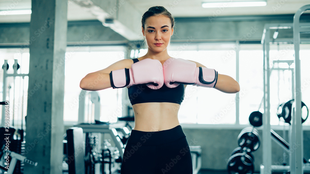Portrait of a confident young athlete woman posing in boxing gloves.Attractive Female Punching A Bag With Boxing Gloves On. Portrait of a confident young athlete woman posing in boxing gloves.Attractive Female Punching A Bag With Boxing Gloves On.