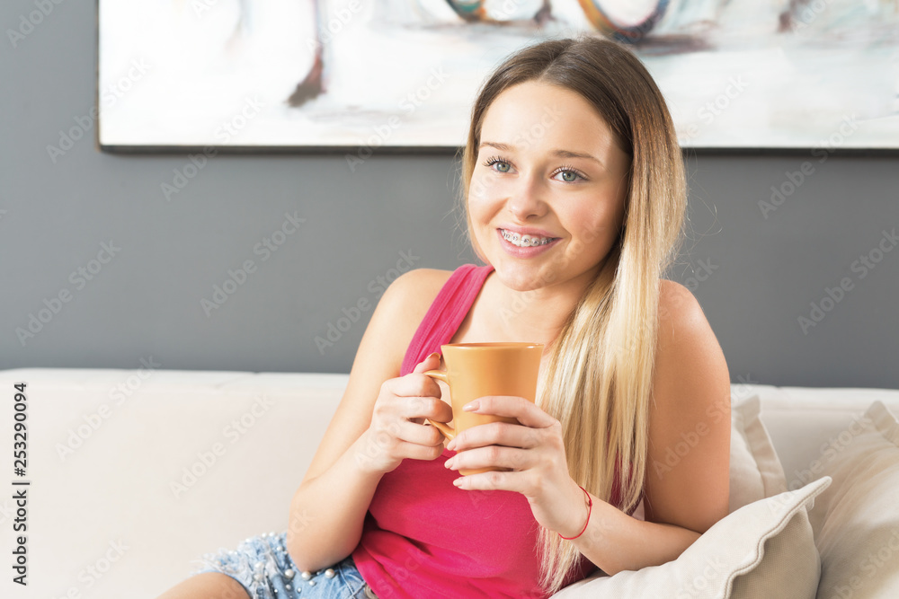 Beautiful young blonde woman drinking coffee on sofa and smiling Beautiful young blonde woman drinking coffee on sofa and smiling